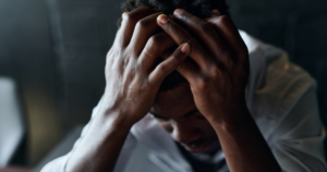 Person with hands over their head, conveying stress or anxiety.