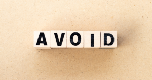 Wooden letter blocks spell the word AVOID on a beige background.