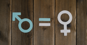 Blue male symbol and white female symbol with an equals sign on a wooden background, symbolizing gender equality.